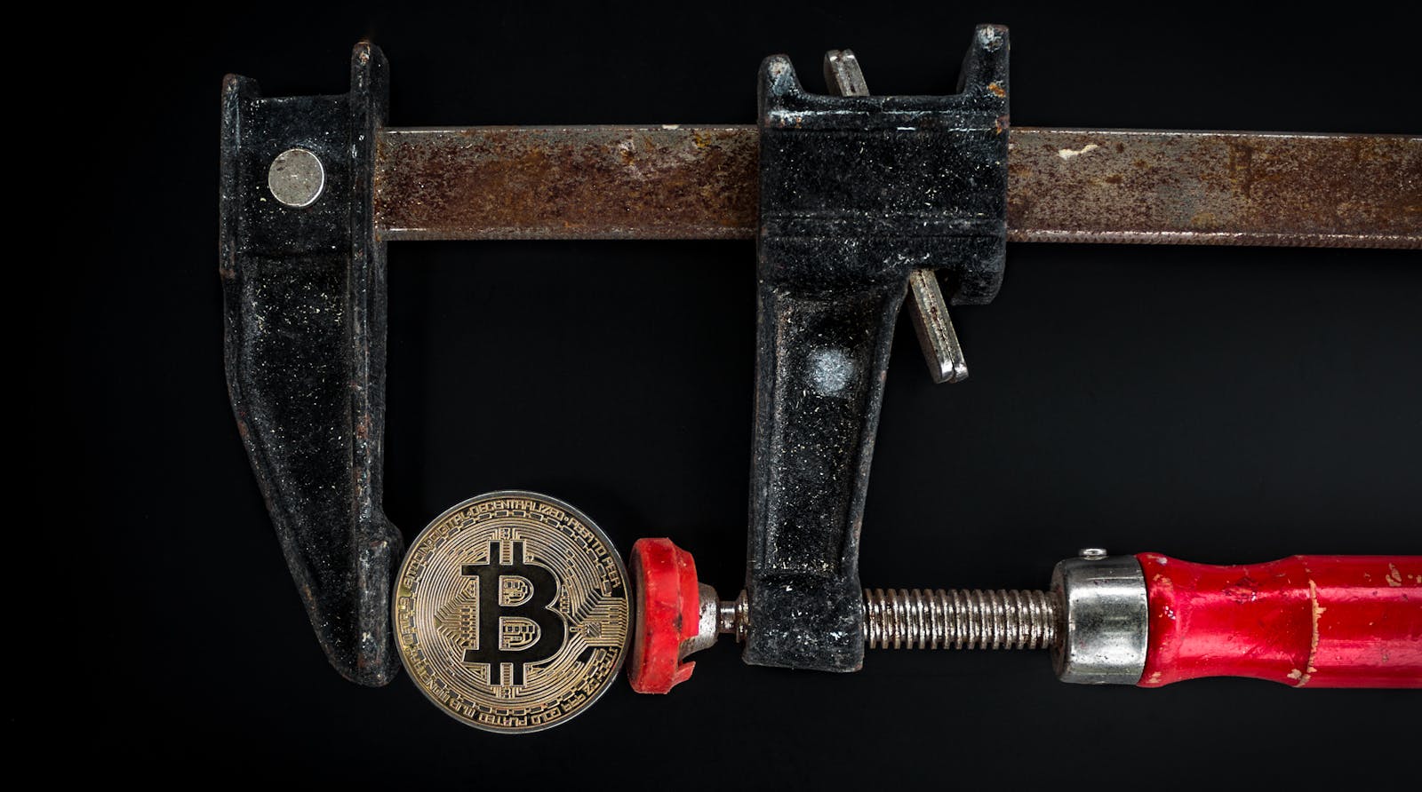 Conceptual image of cryptocurrency represented by a Bitcoin secured in a rusty clamp.