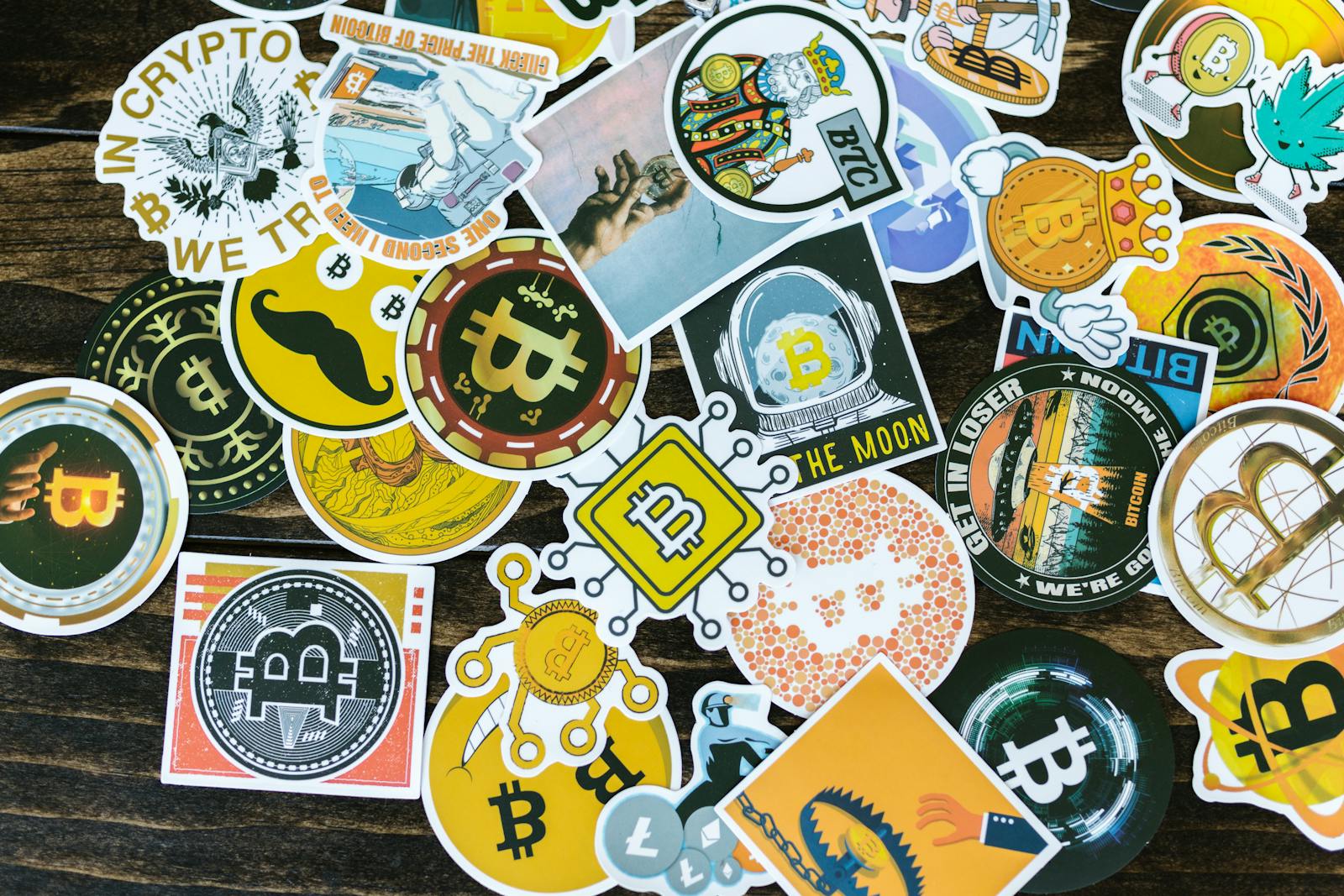 Colorful collection of Bitcoin-themed stickers on a wooden background, ideal for cryptocurrency concepts.