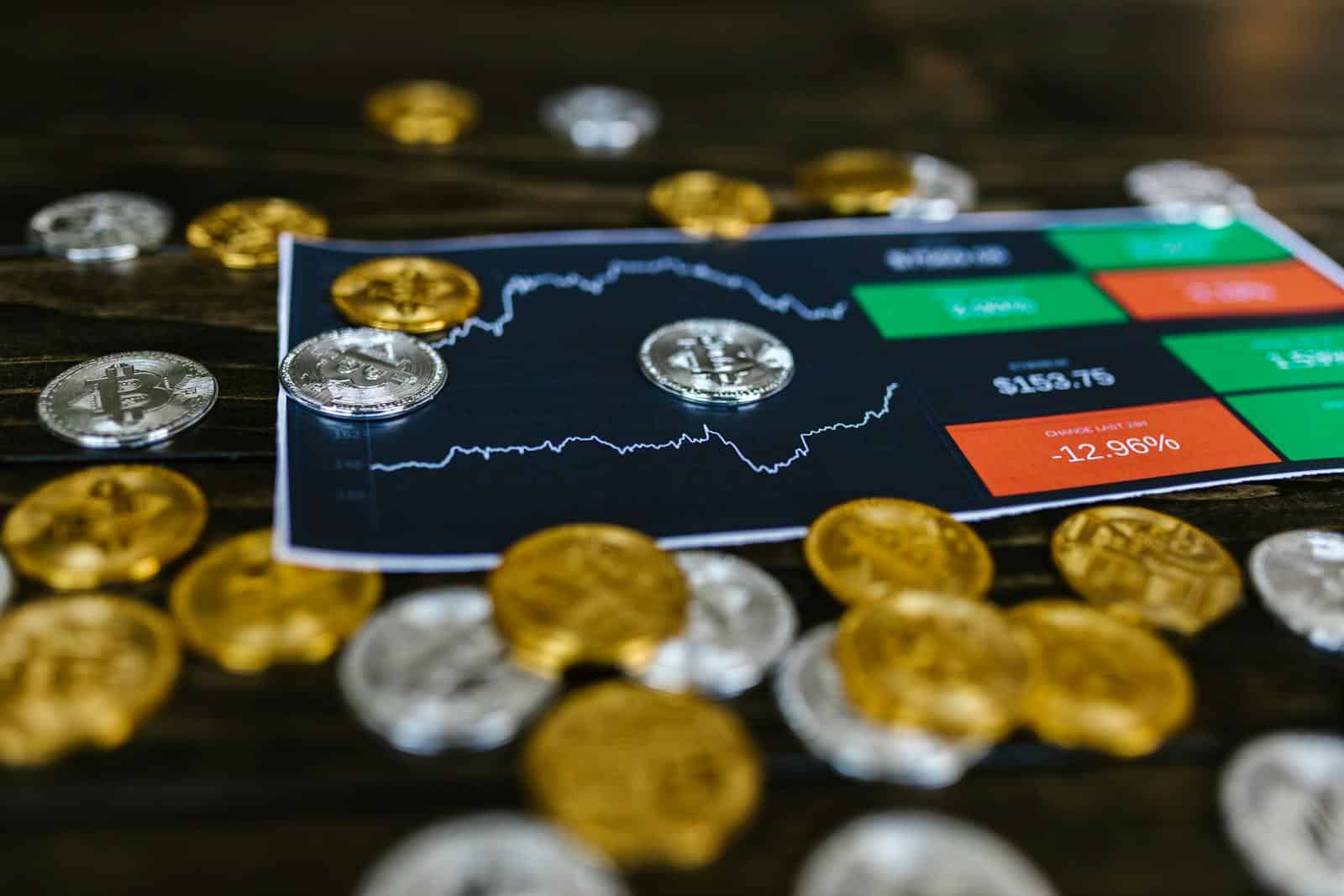 Bitcoin and altcoins on table with digital trading chart indicating market trends and investment details.