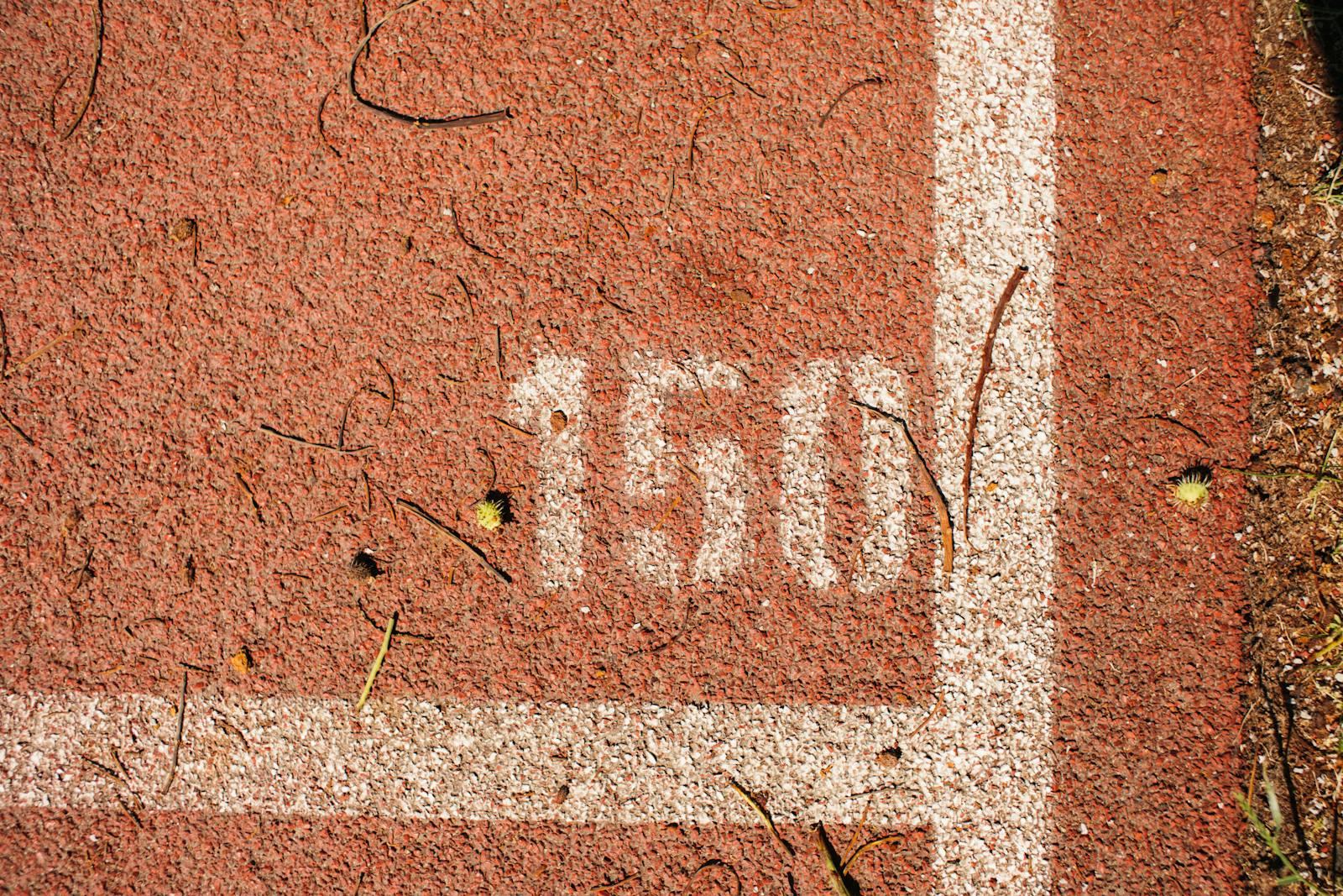 Close-up of a running track showing the number 150 marked on red surface with white lines.