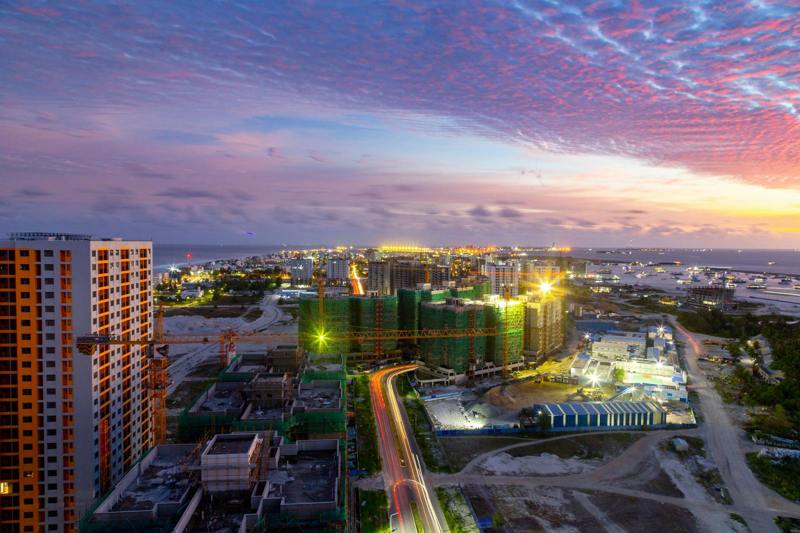 A colorful dusk view of Malé cityscape showcasing construction and city lights.